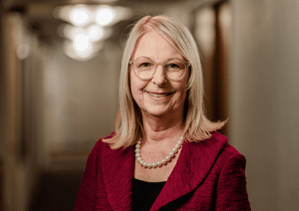Smiling woman wearing glasses and pearls